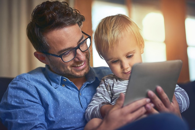 De do's en don'ts van digitale technologie leren Shot van een vader en zoon die thuis een digitale tablet gebruiken op de bank