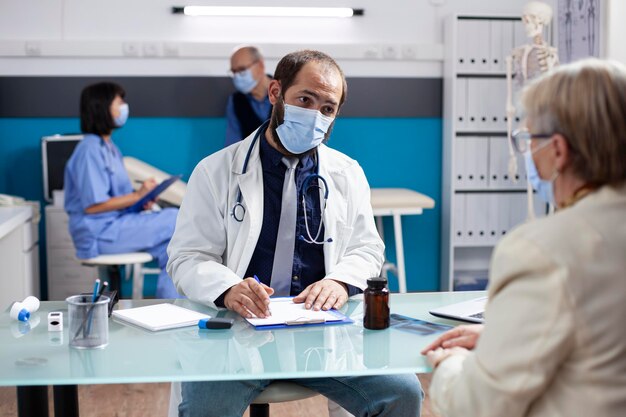 De dokter bespreekt de symptomen met de oude vrouw.