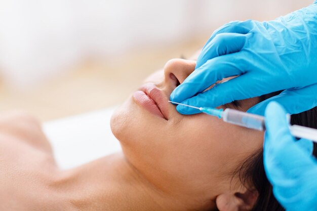 De dokter doet injecties om de lippenlijn te corrigeren.