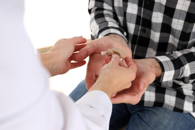 Foto de dokter geeft het gehoorapparaat aan de man, close-up