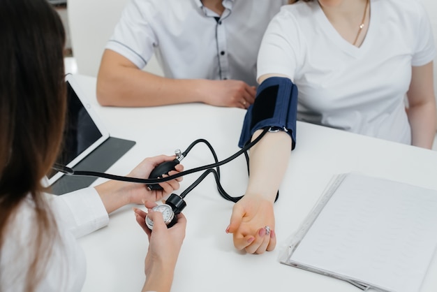 De dokter meet de druk van een zwanger meisje in de kliniek. Zwangerschap en gezondheidszorg