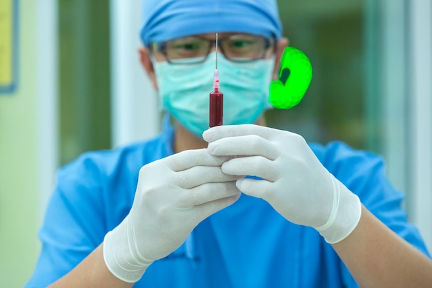 Foto de dokter met een injectiespuit met bloedmonster en een rek met andere monsters technicus die een bloedspuitmonster vasthoudt voor studie