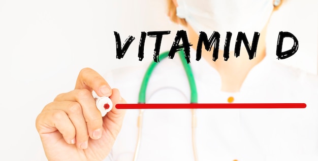 De dokter schrijft de tekst VITAMINE D met een stift. Medisch concept.