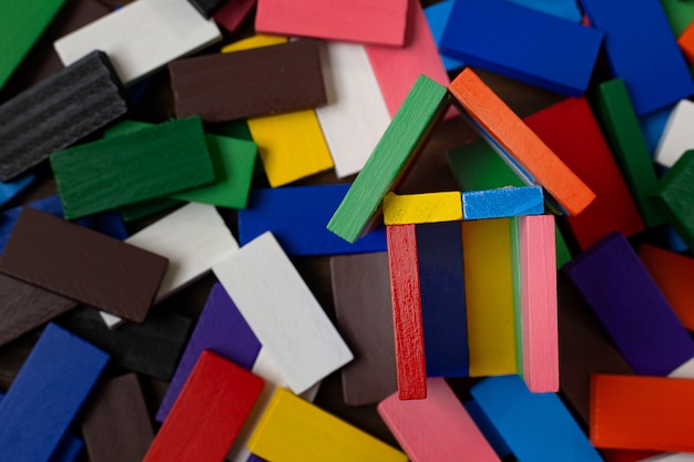 De domino-multikleur bouwt thuis op houten tafel.