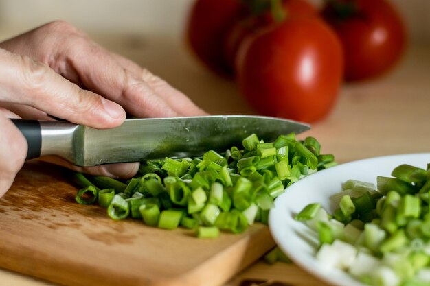 De donkere fotografie van snijplank met tak van tomaten en lente-ui