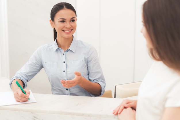 De donkerharige vrouw werkt bij de receptie.