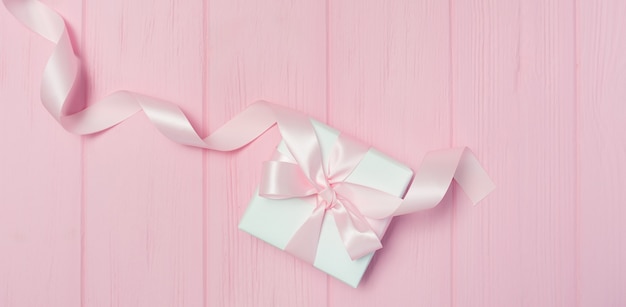 De doos van de Gift van de banner met lint op roze houten achtergrond met plaats voor uw tekst