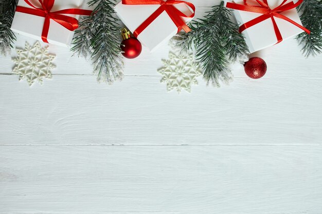 De doos van de gift van Kerstmis, dennentakken, rode decoraties op witte houten achtergrond, Kerstmis, winter, nieuwjaar concept, plat leggen, bovenaanzicht, kopie ruimte