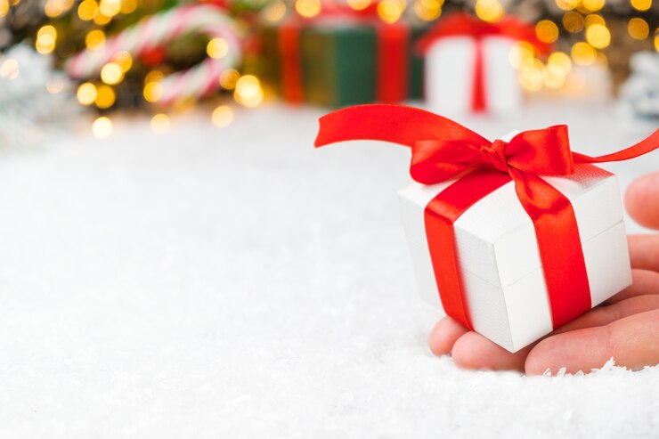 Foto de doos van de gift van kerstmis met rood lint en strik op de sneeuw