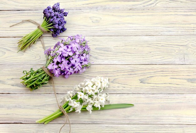 De drie boeketten van bloemenhyacinten muscari en gillyflower op houten close-up als achtergrond