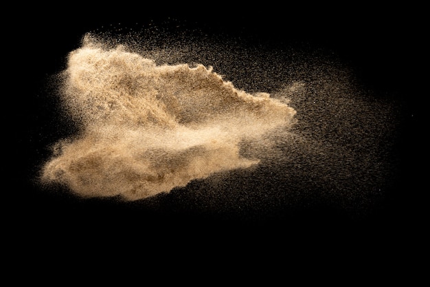 De droge explosie van het rivierzand De bruine plons van het kleurenzand tegen zwarte achtergrond.