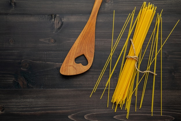 De dunne spaghetti op zwarte houten achtergrond.