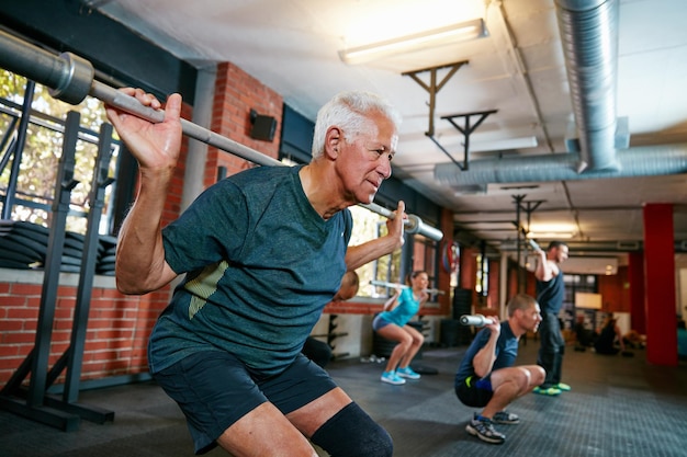 De echte training begint wanneer je wilt stoppen Foto van een oudere man die aan het trainen is in een fitnessclub met wazige mensen op de achtergrond