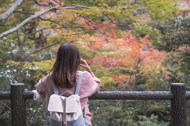 De eenzame vrouw die zich gelet op verzonken bevinden en bladeren bekijken verandert kleur in de herfst