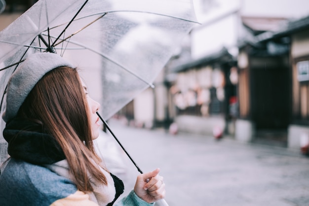 De eenzame vrouw met paraplu wacht op de regen op de straat in Japan.