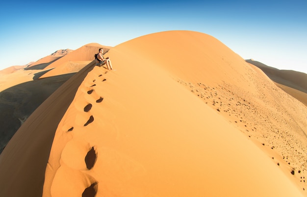 De eenzame zitting van de mensenreiziger op zand bij Duin 45 in Sossusvlei Namibië