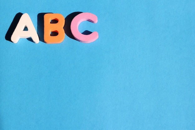 De eerste letters van het abc van het engelse alfabet op een blauwe achtergrond. engels voor beginners.