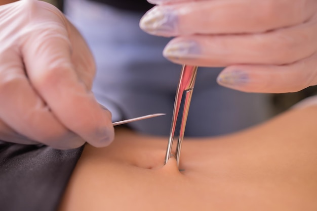 De eerste piercing dressing de oorbellen op de navel vrouwelijke piercing