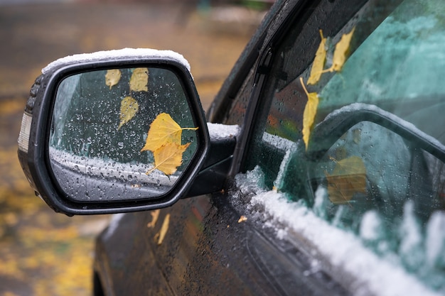 De eerste sneeuw op de spiegel van de auto.