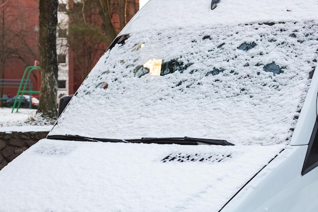 De eerste sneeuw op de voorruit van een auto