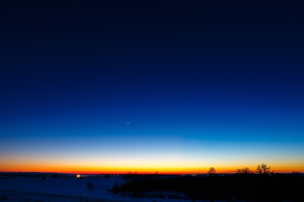 De eerste sterren op de achtergrond van een heldere zonsondergang.