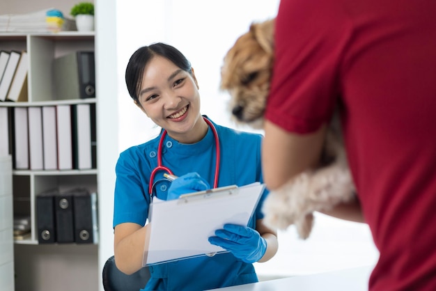 De eigenaar van de hond brengt een zieke hond naar het kantoor van de dierenarts voor behandeling De vrouwelijke dierenarts onderzoekt de gezondheid van een hond in het kantoor van het dierenarts.