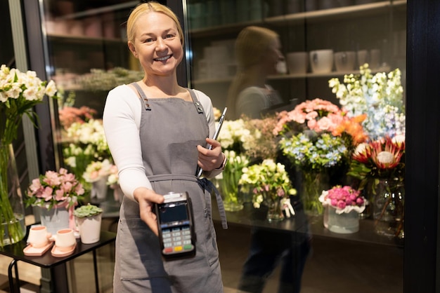 De eigenaar van een bloemenwinkel biedt aan om een boeket te betalen met een bankkaart via een betaalautomaat voor