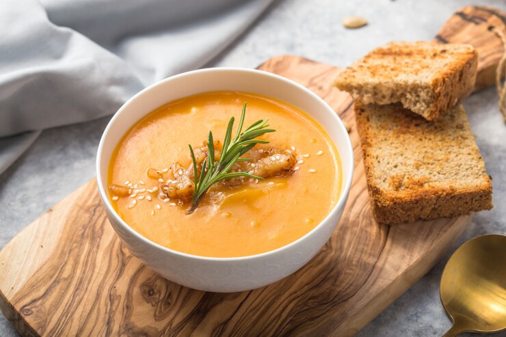 Foto de eigengemaakte soep van de de pompoenroom van de herfst butternut pompoen met brood en zaden.