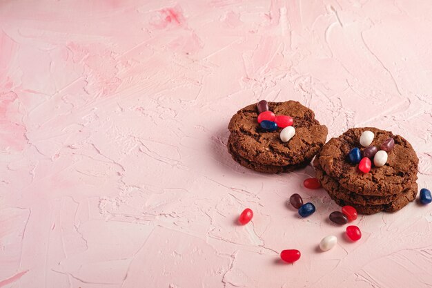 De eigengemaakte stapel van de chocoladekoekjes van de haverchocolade met graangewas met sappige geleibonen op geweven roze oppervlakte, het exemplaarruimte van de hoekmening