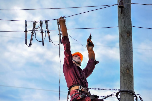 De elektricien meet de spanning op de hoogspanningslijn voordat hij deze repareert.