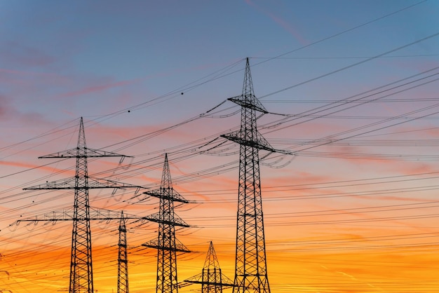 De elektrische toren van de silhouethoogspanning op zonsondergangtijd en hemel op de achtergrond van de zonsondergangtijd