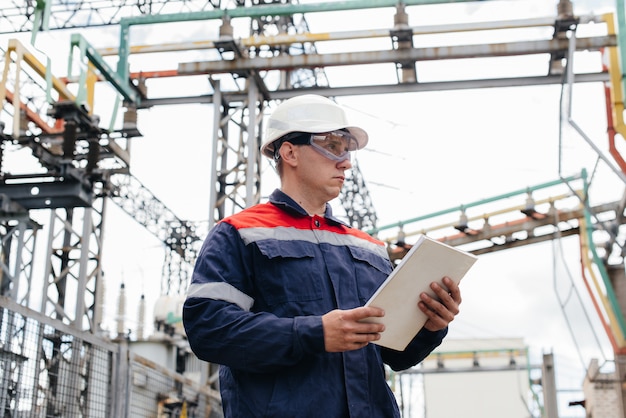 De energie-ingenieur inspecteert de apparatuur van het onderstation. Energietechniek. Industrie.