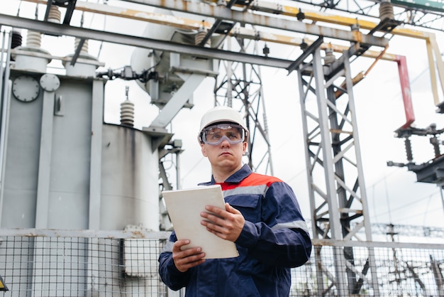 De energie-ingenieur inspecteert de apparatuur van het onderstation. Energietechniek. Industrie.