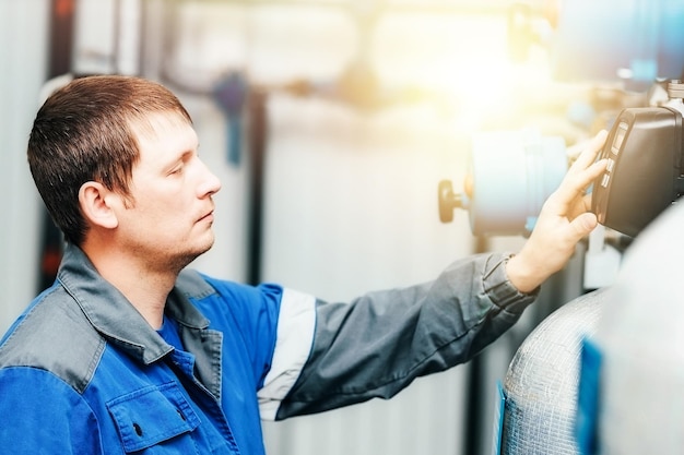 De energietechnicus controleert het systeem en de meetwaarden in de productiefaciliteit binnenshuis. Dit is een echte blanke werker