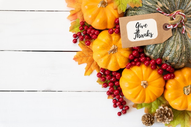 De esdoornbladeren van de herfst met pompoen en rode bessen op houten achtergrond. thanksgiving concep