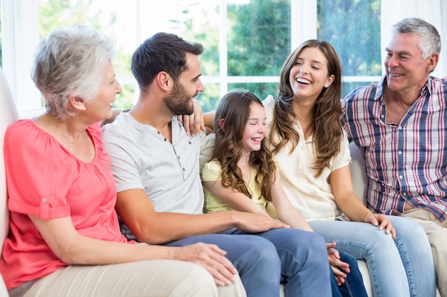 De familie die van meerdere generaties terwijl het zitten op bank glimlachen