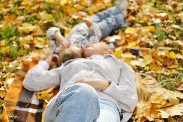 Foto de familie heeft plezier in het park meisje en moeder liggen op een deken en kijken naar herfstbladeren