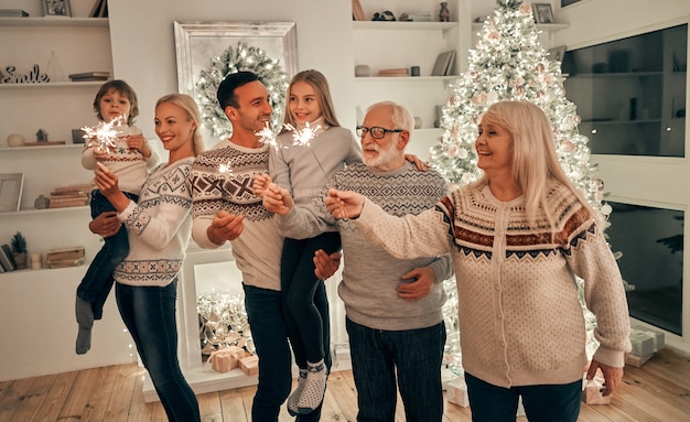 De familie met sterretjes die bij de kerstboom staan