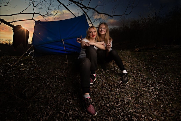 De familie moeder en dochter voor het weekend gingen naar het platteland voor een picknick zitten bij het vuur in het wild met een tent bakken aardappelen drinken hete thee