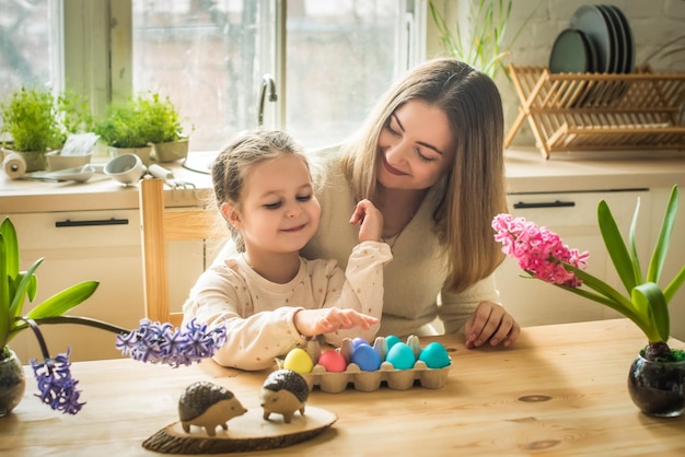 De familie schildert kleurrijke paaseieren moeder en dochter vieren lentevakantie samen jonge vrouw man en meisje die traditionele landschappen kleuren