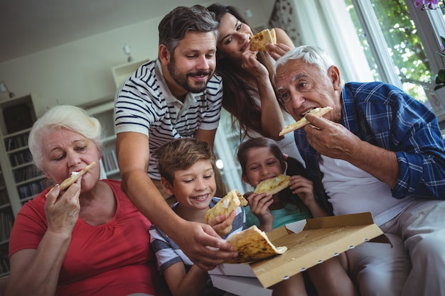 De familie van meerdere generaties die pizza hebben samen