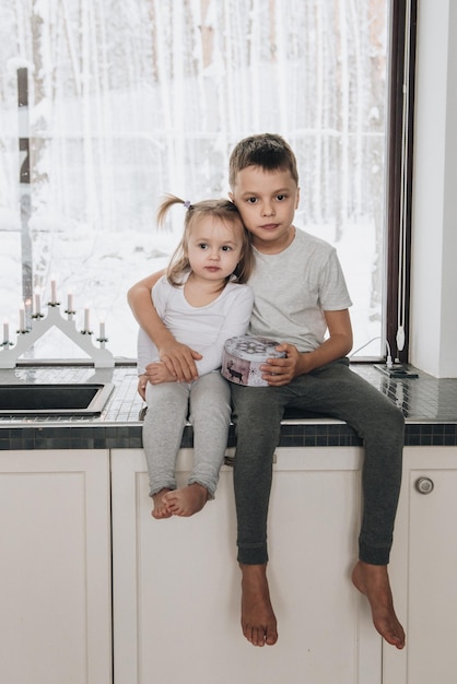 De familie zit bij het raam en kijkt naar het winterbos. Goede nieuwjaarsgeest. Ochtend in pyjama.