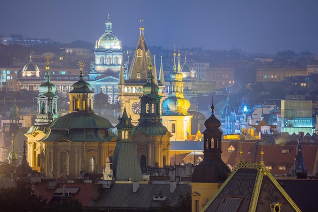 De fantastische oude stadsdaken van Praag tijdens schemering met torensklok en nachtverlichting Tsjechische Republiek Europese beroemde bezienswaardigheid