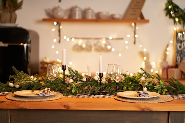 De feestelijke kersttafel is versierd met takken van een kerstboom, kaarsen en guirlandes