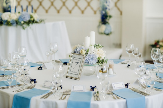De feesttafel is gedecoreerd in lichte kleuren met blauwe servetten en bloemen zonder eten