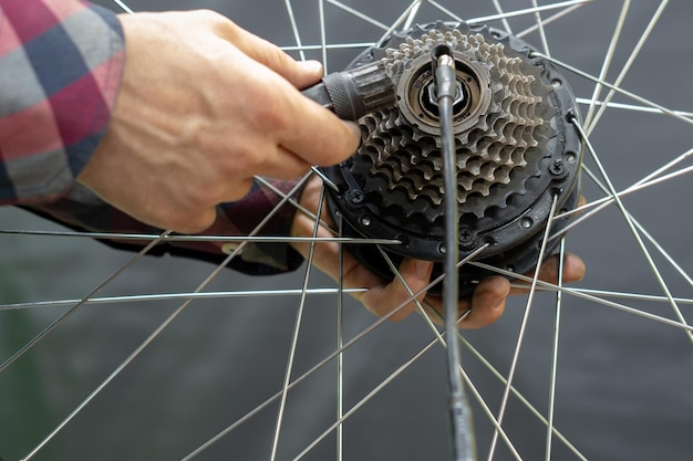 De fietsmonteur installeert een nieuwe cassette op het motorwiel reparatie van elektrische fietsen monteur hand en moersleutel close-up vervanging van versleten apparatuur op een mountainbike