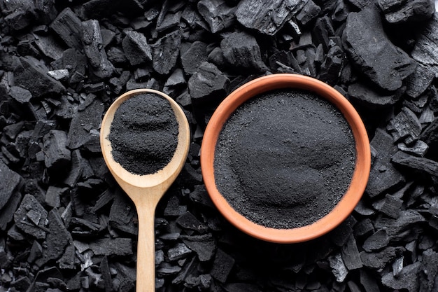 De fijngemalen zwarte houtskool werd in een kopje op een grote stapel houtskool geplaatst.