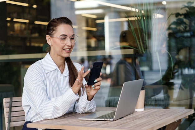 De financier werkt online met behulp van een computer. Een vrouw met een bril en een moderne laptop op kantoor