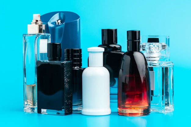 De fles van het mensenparfum op blauwe dichte omhooggaand