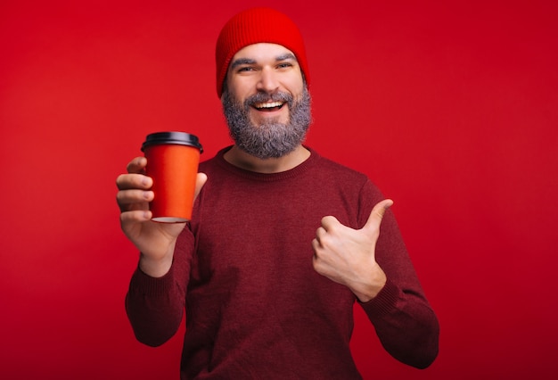 De foto van de gelukkige te gaan kop van de mensenholding van koffie en het tonen beduimelt omhoog